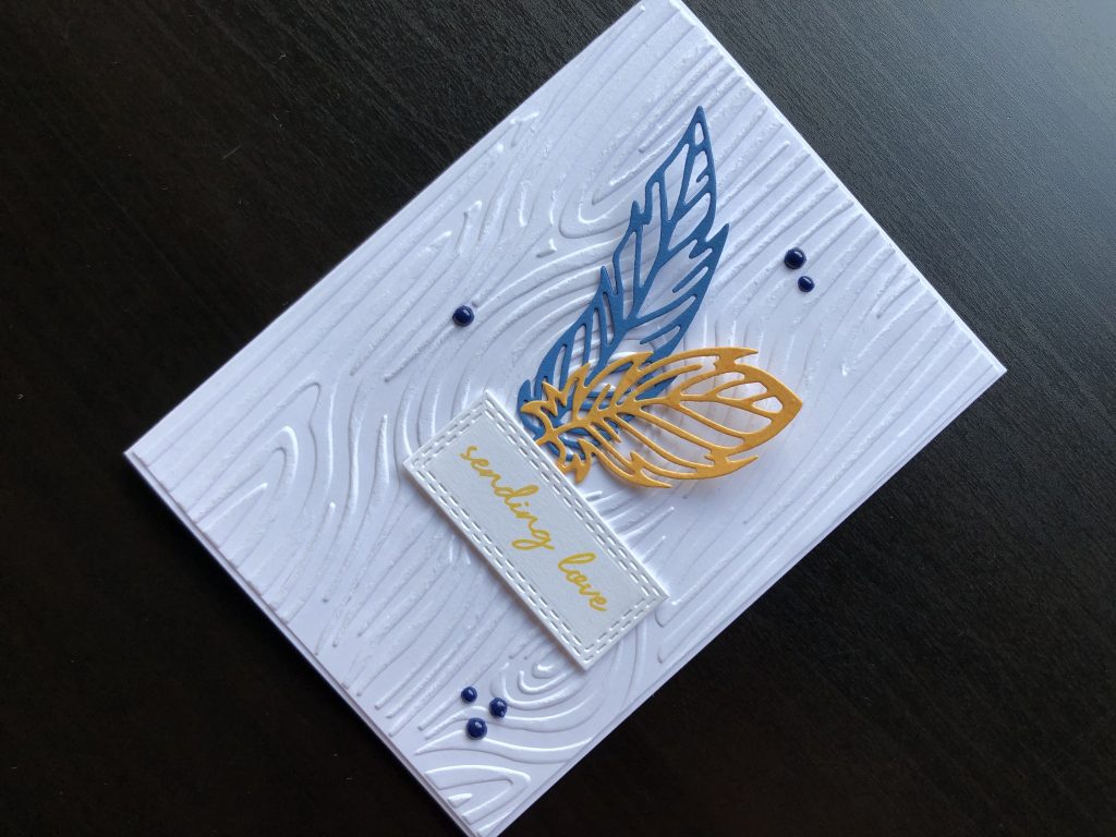 Hand made card with woodgrain background, die cut feathers and stamped greeting.