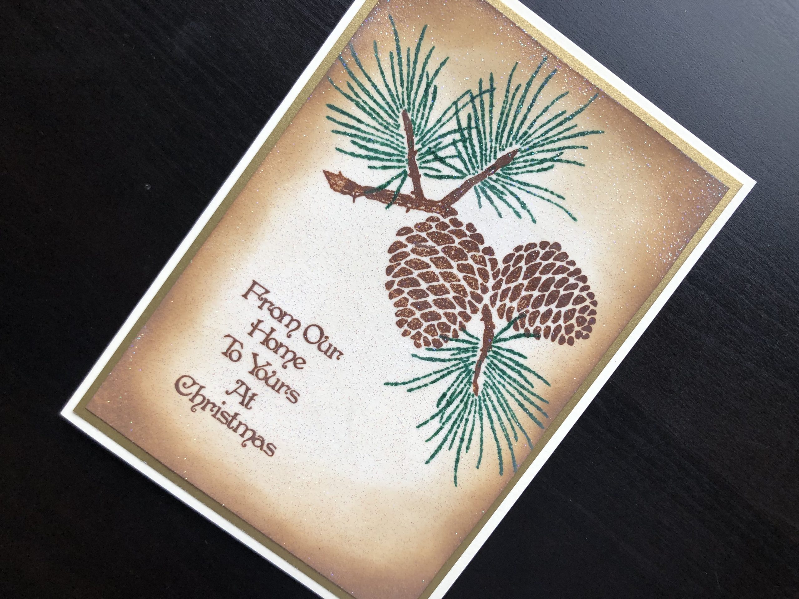 hand made Christmas card with stamped pine cones and glitter embossing