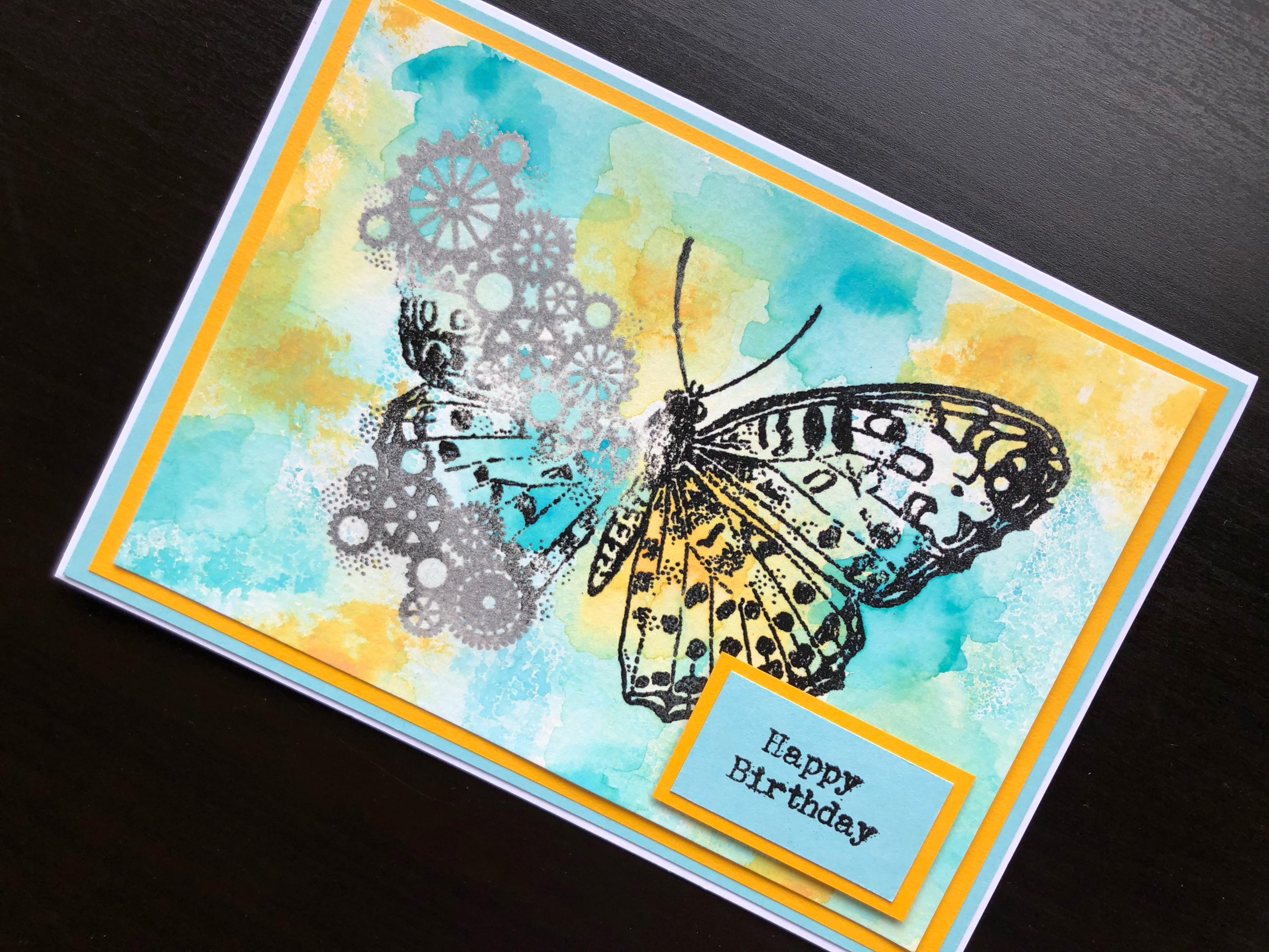 hand made birthday card with a heat embossed steampunk butterfly on an inked background