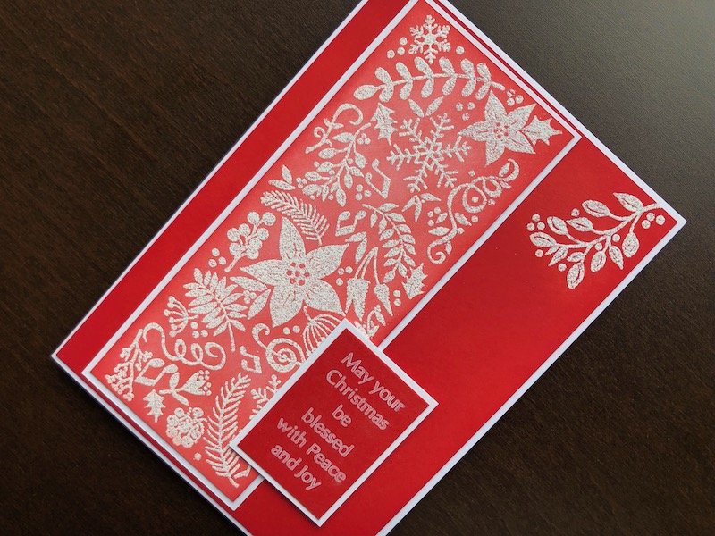 Hand made Christmas card with stamped and heat embossed festive panel and foliage