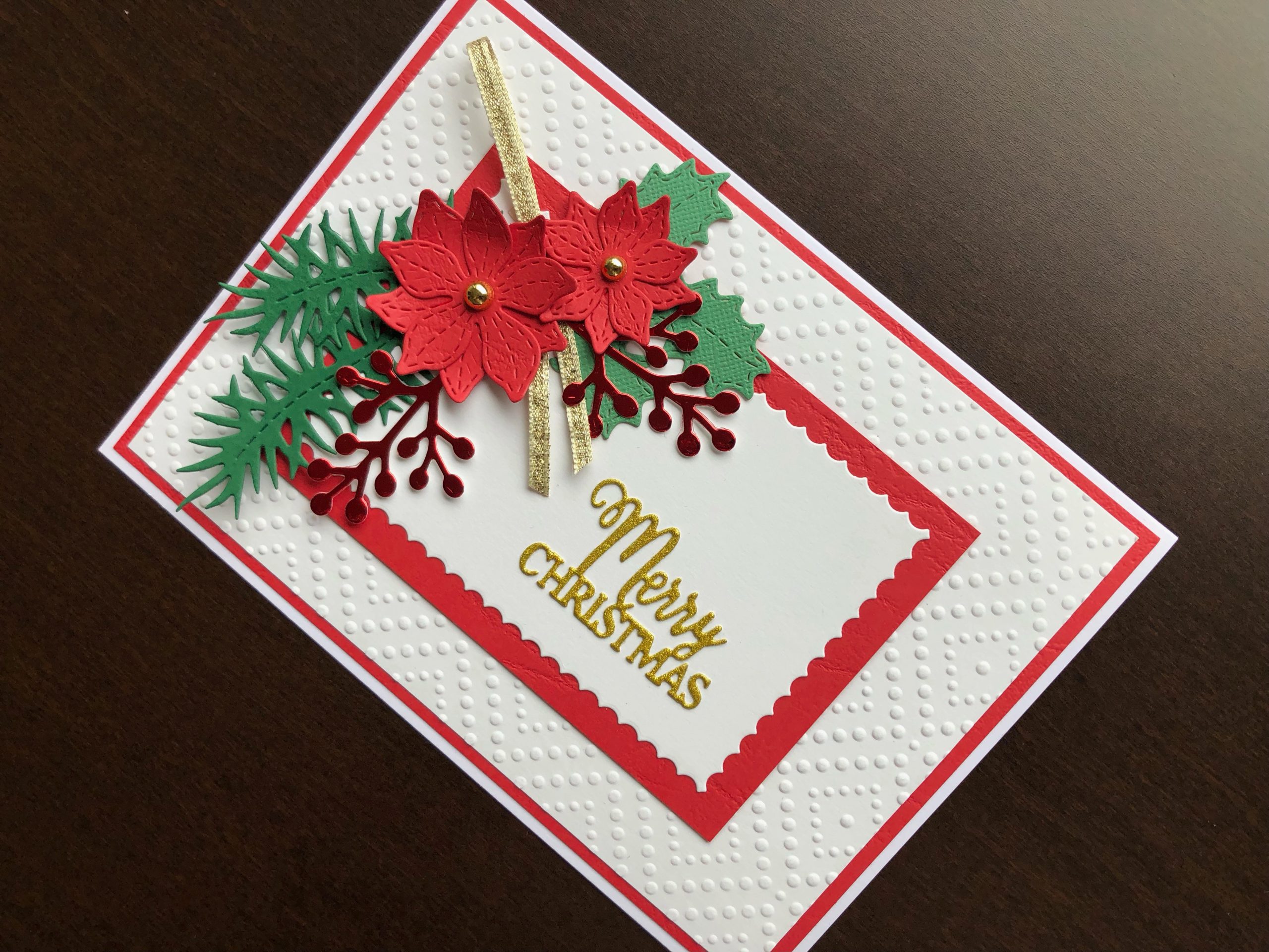 Hand made Christmas card with die cut poinsettias, winter foliage and sentiment