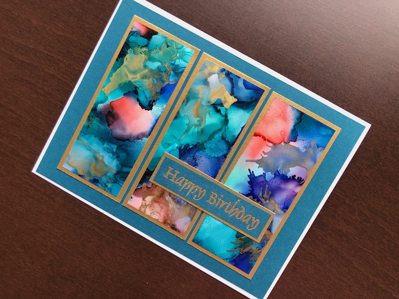 Hand made birthday card with alcohol ink panels and heat embossed sentiment strip.