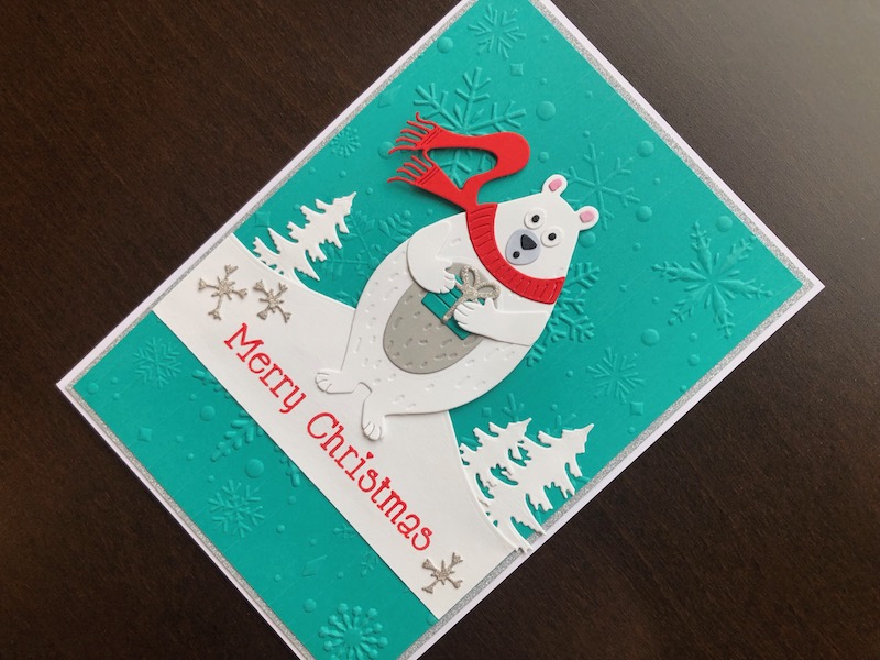 Hand made Christmas card with embossed snowflake background and die cut polar bear with a gift.
