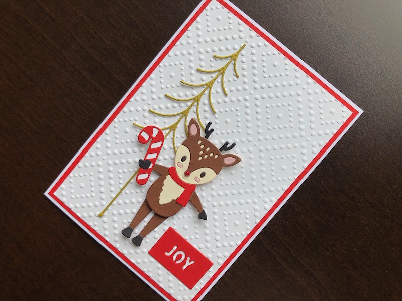 Hand made Christmas card with a die cut dancing reindeer and Christmas tree on an embossed background.