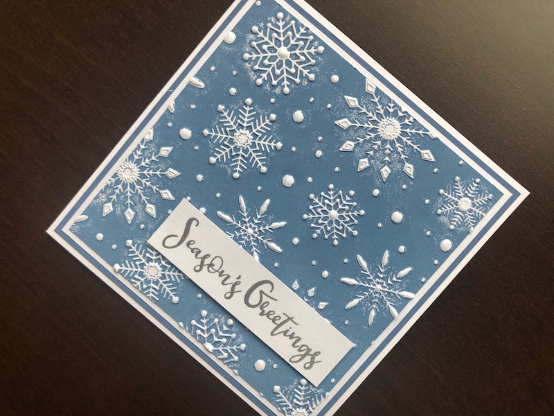 Hand made Christmas card with inked and embossed snowflake background and heat embossed Seasons Greetings sentiment