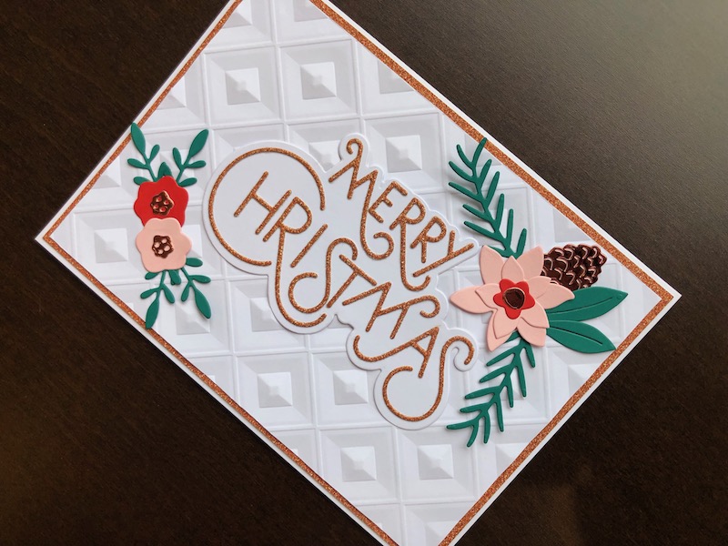 Hand made Christmas card with stylish merry Christmas sentiment, die cut pine cones and branches and poinsettias.