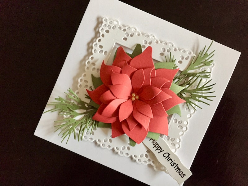 Hand made Christmas card with red die cut poinsettia in a white frame