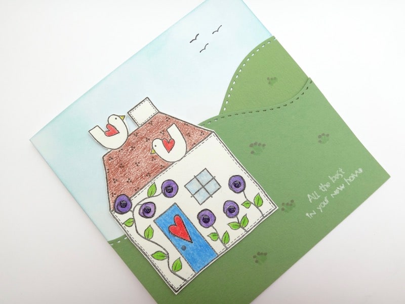 New home card with die cut stitched hillsides and stamped house.