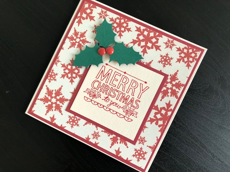 Christmas card with stamped hand drawn greeting and die cut holly leaves